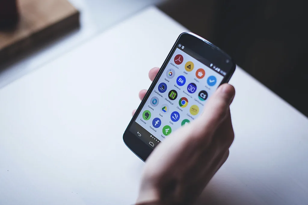 Mano sosteniendo un teléfono con las aplicaciones de redes sociales en pantalla