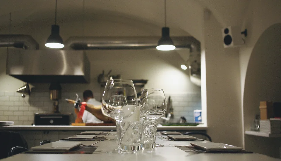 Interior de un local de hostelería con la barra y la cocina al fondo