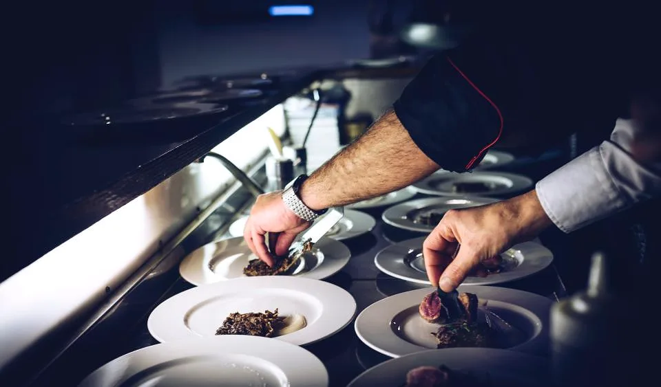 Cocinero emplatando un plato en el pase de un restaurante